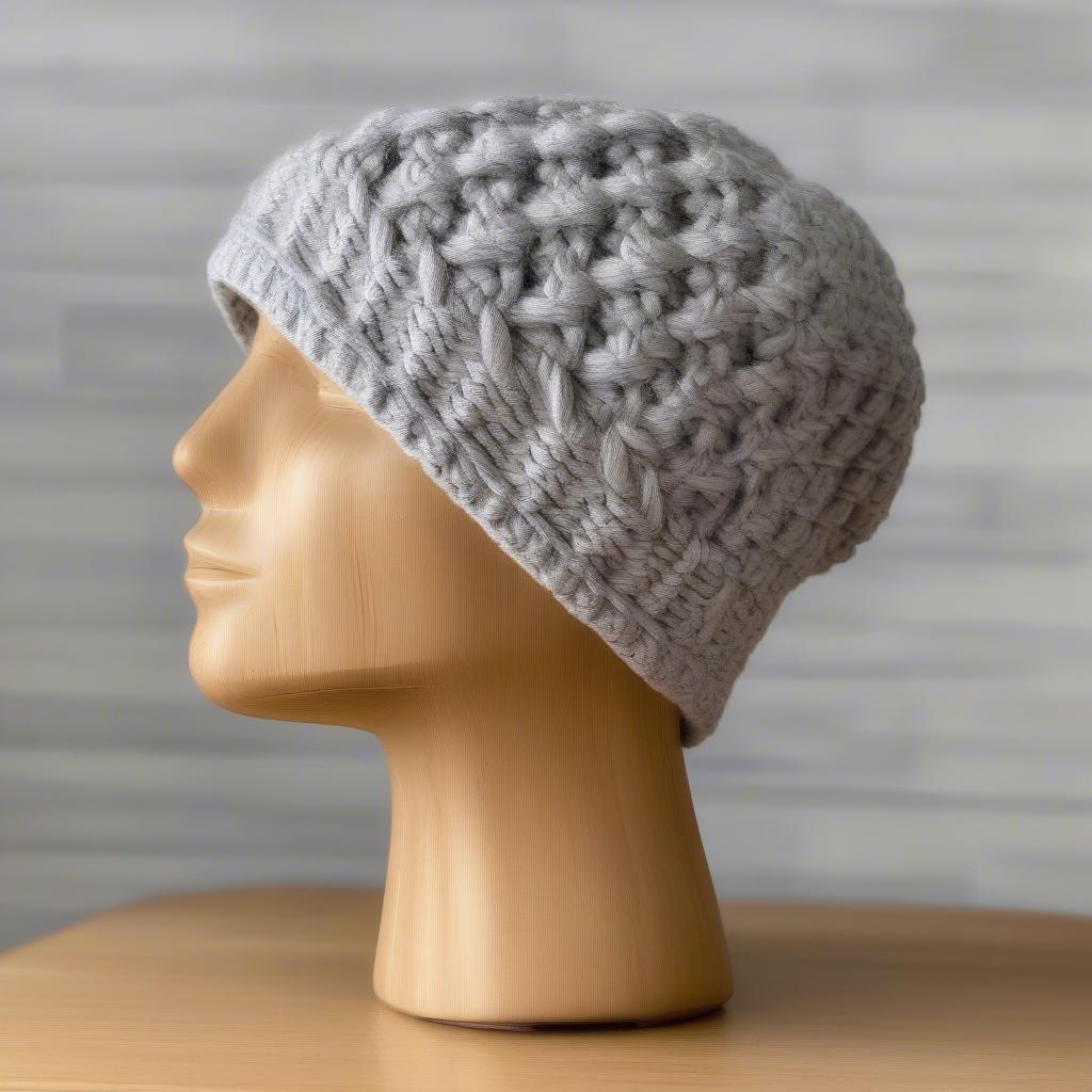 A finished crochet basket weave hat displayed on a wooden mannequin head.