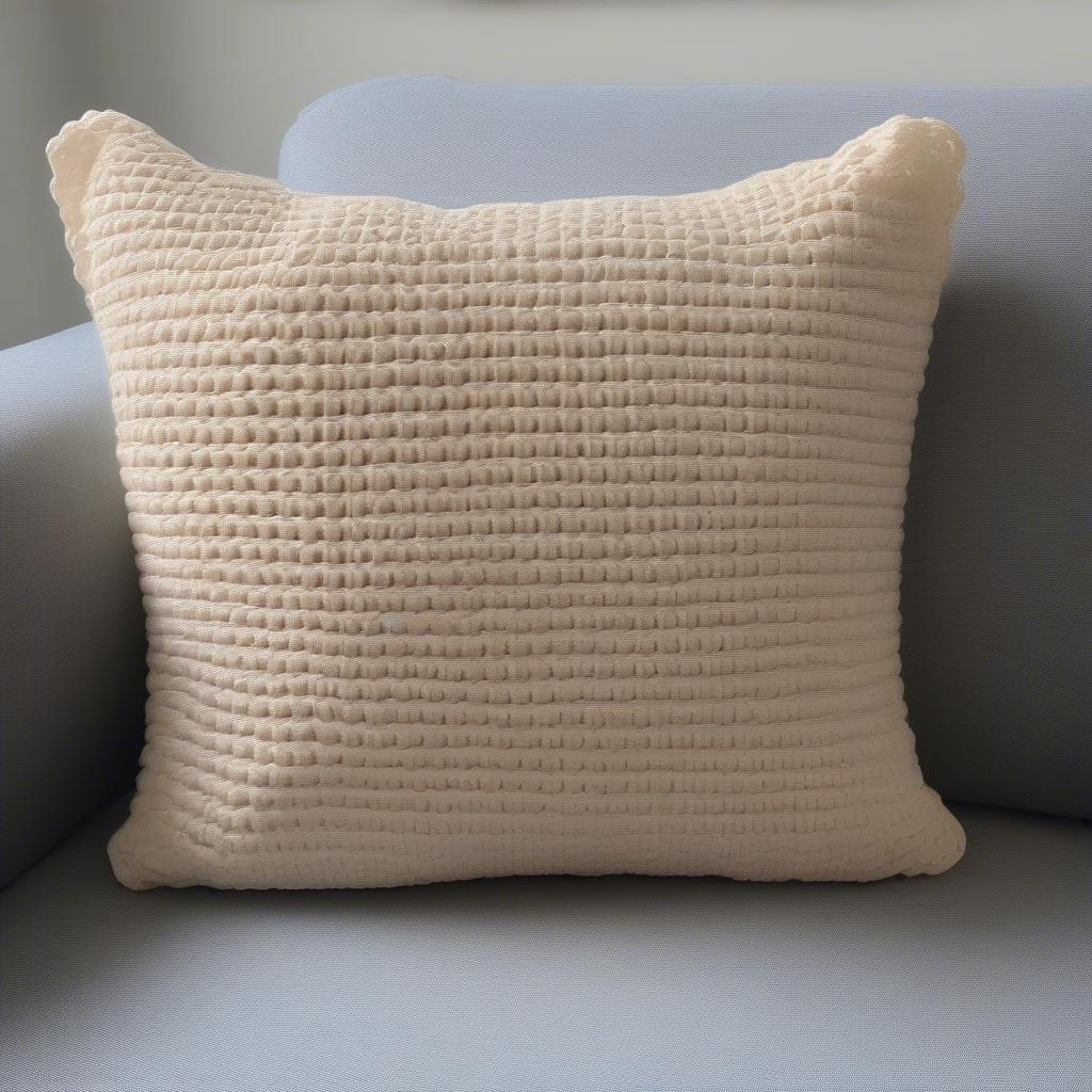 A completed crochet basket weave cushion cover, showcasing its texture and placement on a sofa.