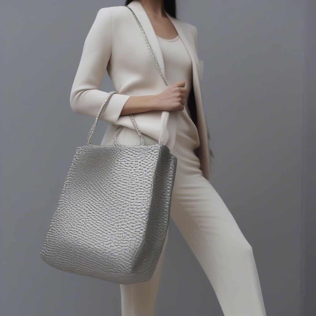 A woman stylishly carrying a woven silver bag