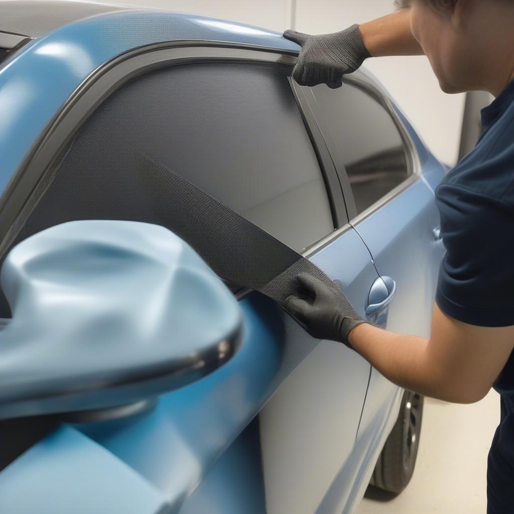 Applying basket weave vinyl wrap to a car door, demonstrating the careful process of smoothing and adhering the vinyl.