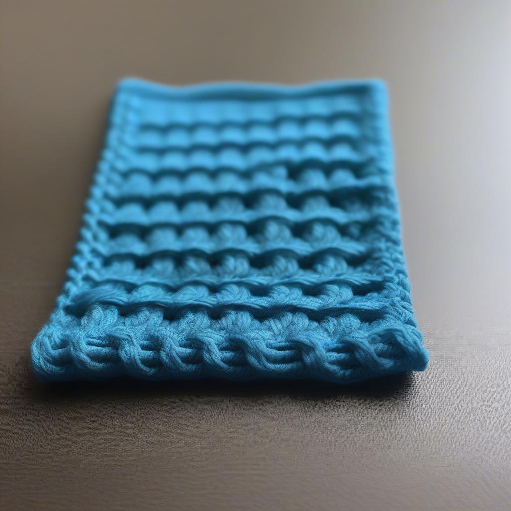 Close-up of a blue basket weave dishcloth showcasing the intricate stitch detail.