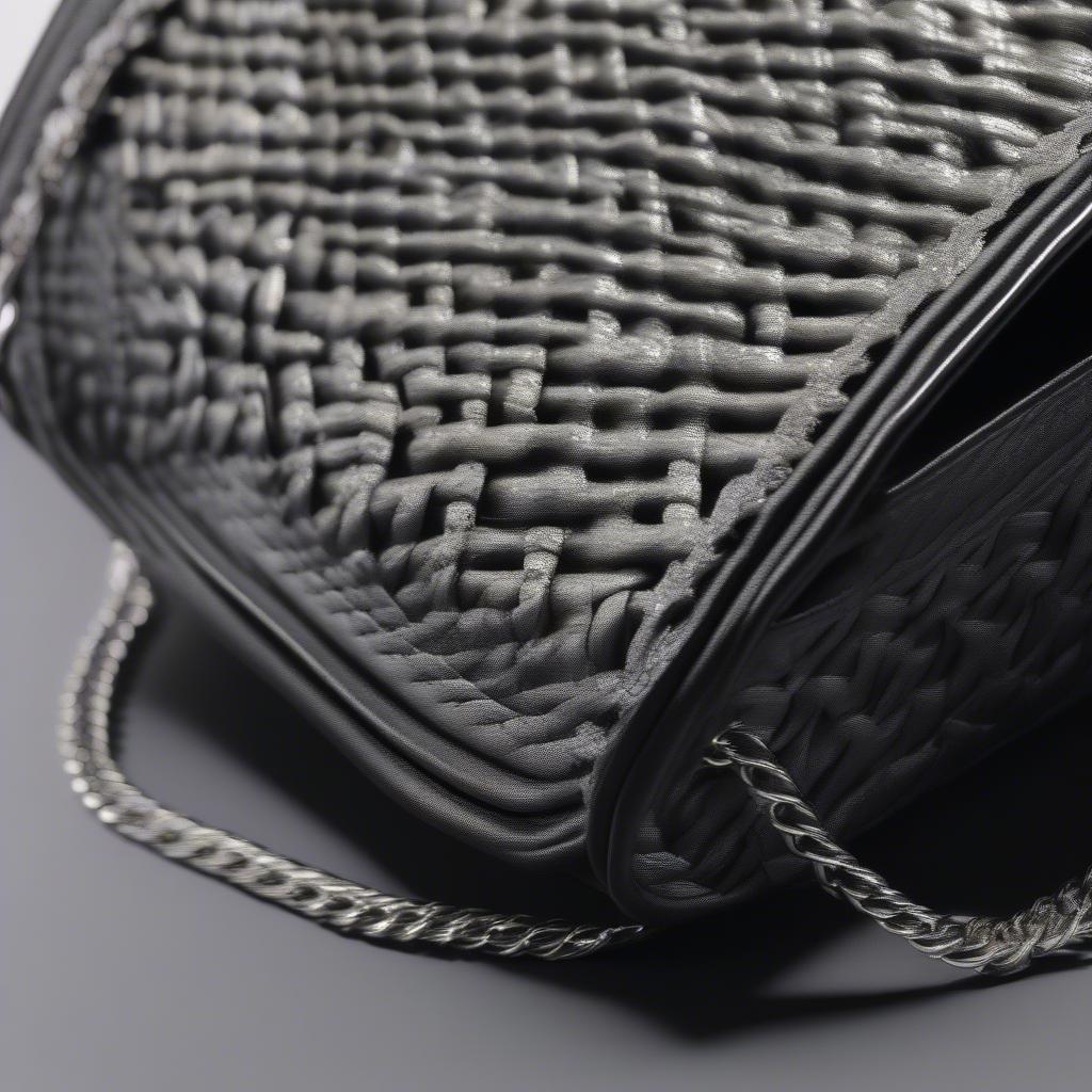 Close-up of a black biker woven chain shoulder bag showing the intricate weave and the metallic chain strap.