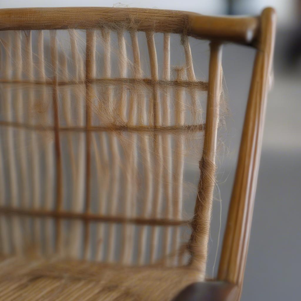 A close-up of a damaged chair seat, showing broken cane and loose weaving.