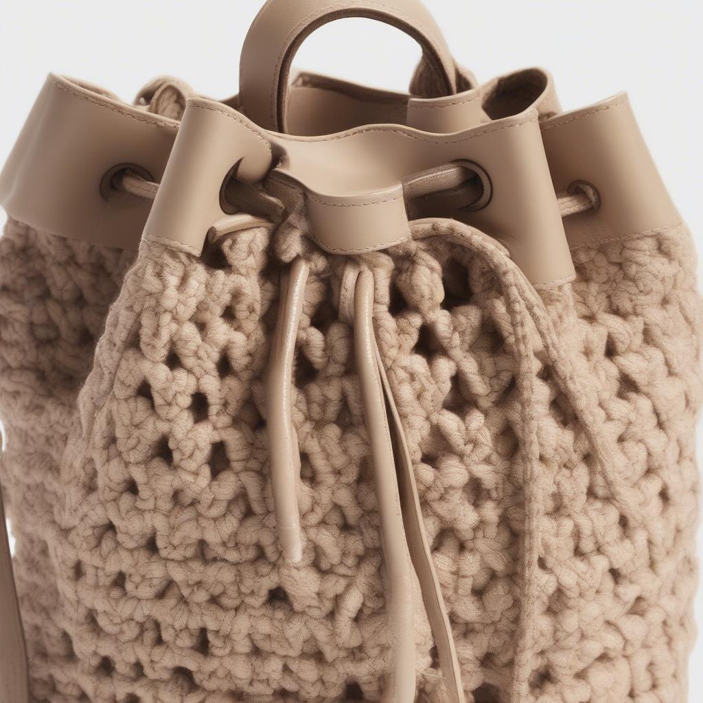 Close-up view of a Nine West crochet woven bucket bag showing the intricate details of the crochet work and the pull string closure.