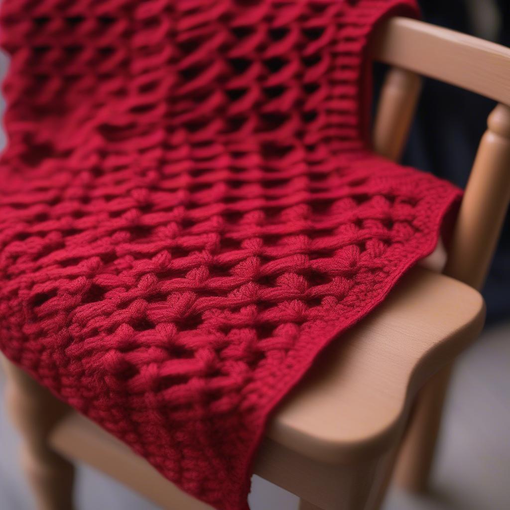 Close-up view of a red heart basket weave crochet scarf, showcasing the intricate texture and stitch definition.