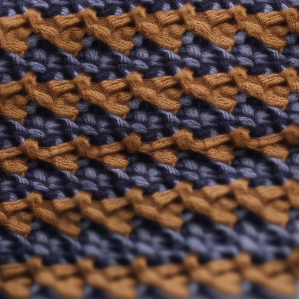 A close-up image of a knitted swatch showcasing the 2 color basket weave knit stitch. The swatch clearly demonstrates the alternating blocks of color, creating the characteristic woven texture.