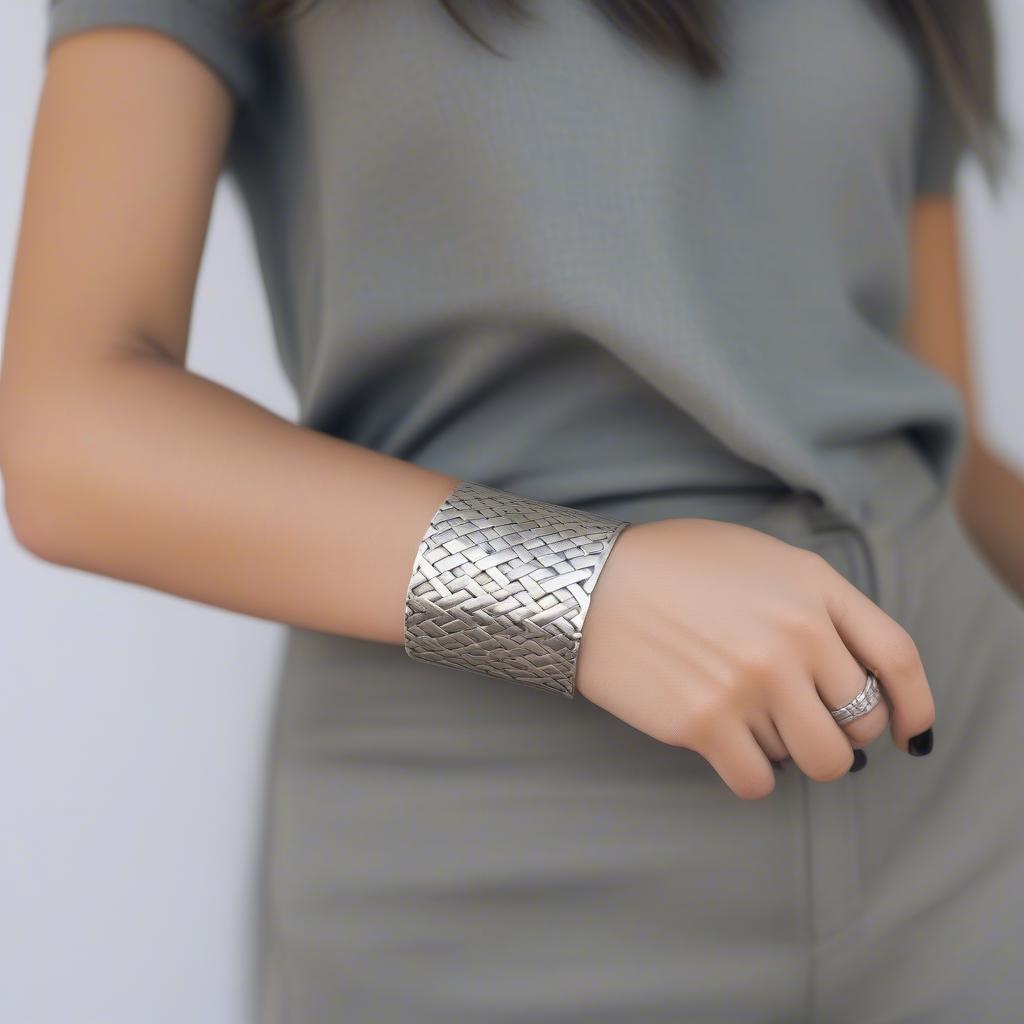 A woman elegantly wearing a silver basket weave cuff bracelet with a casual outfit